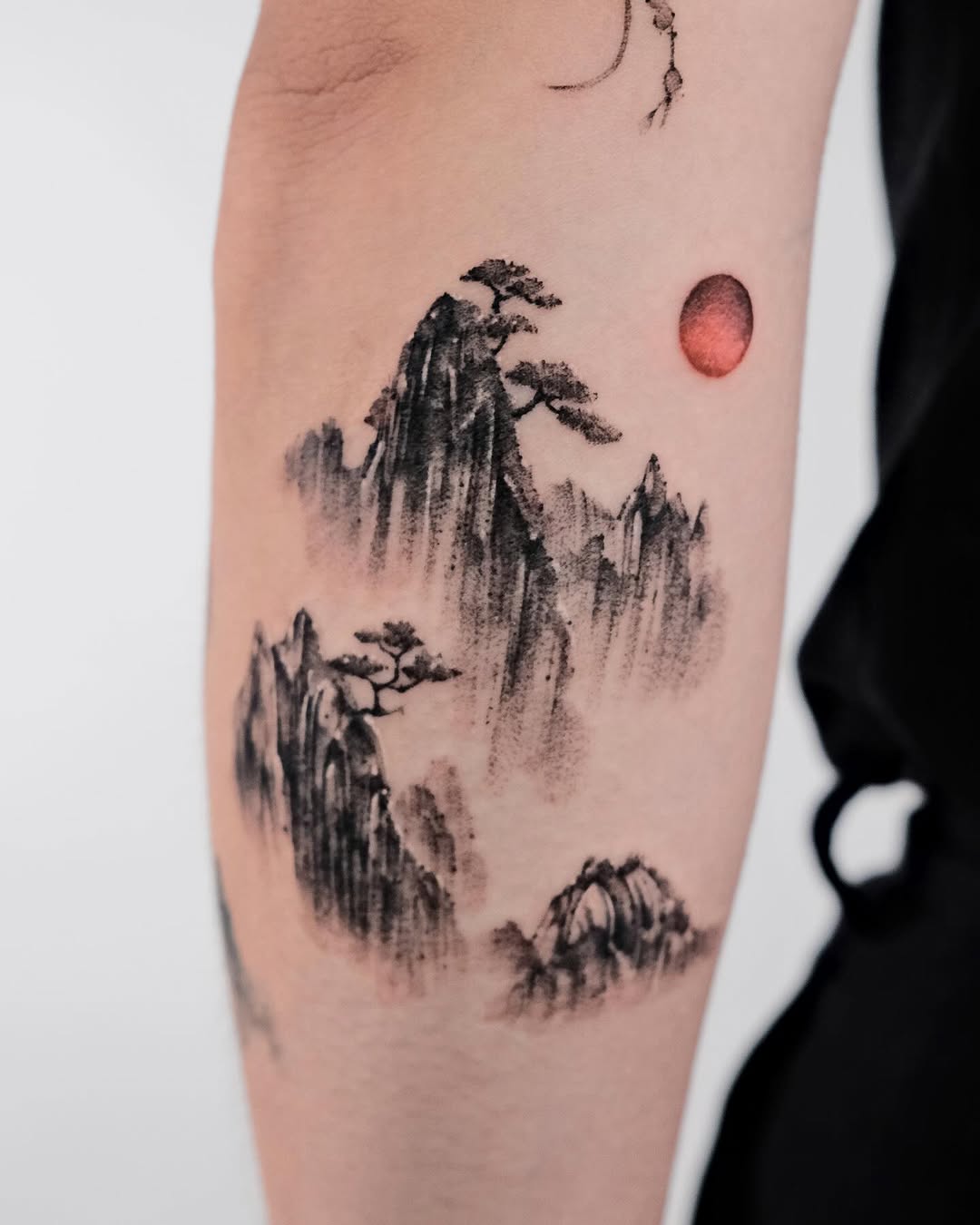 Intricate mountain tattoo with red sun highlight