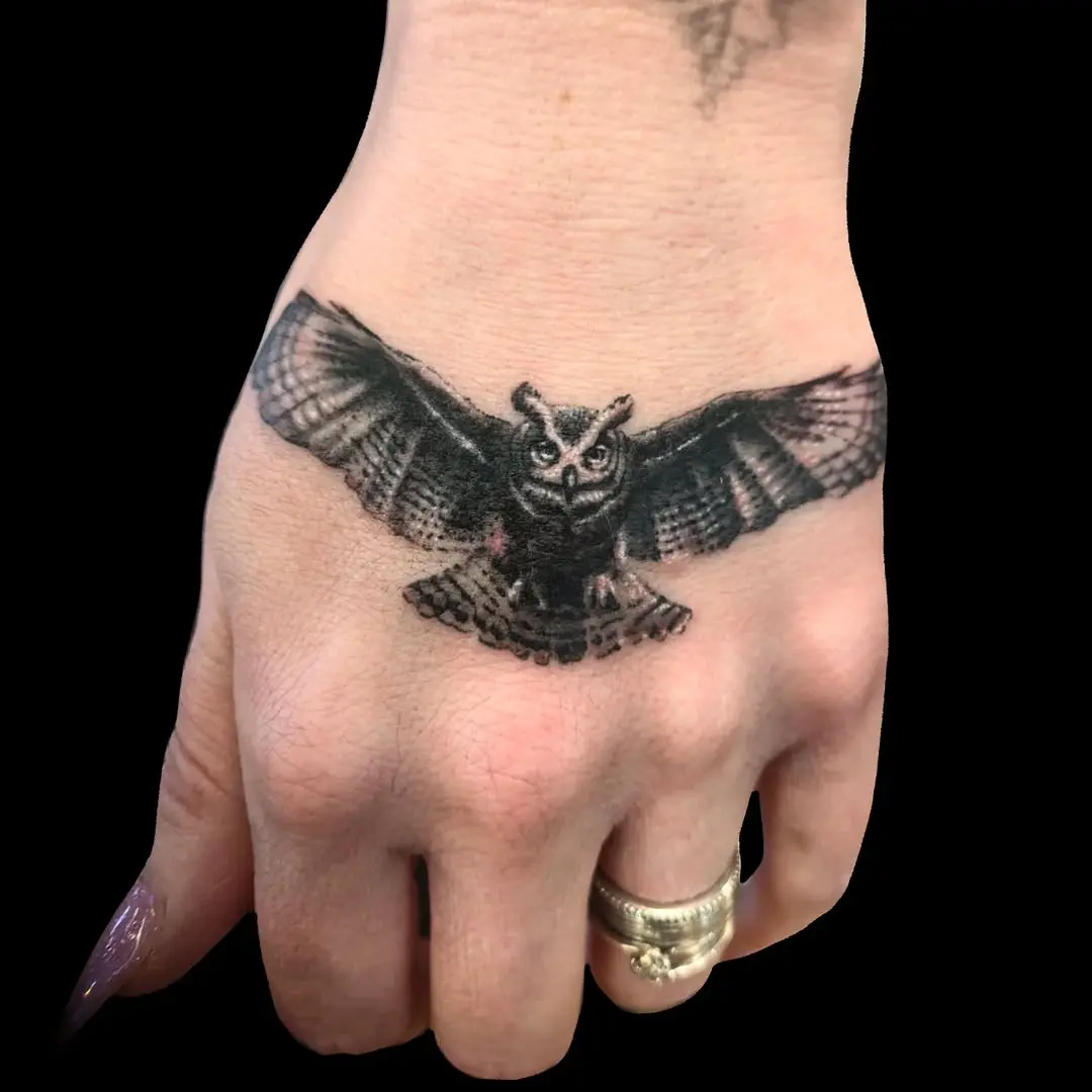 Striking owl tattoo in flight on hand