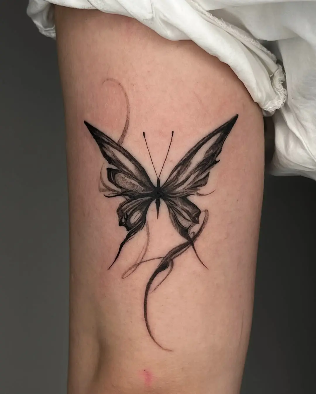 Elegant black butterfly tattoo on thigh