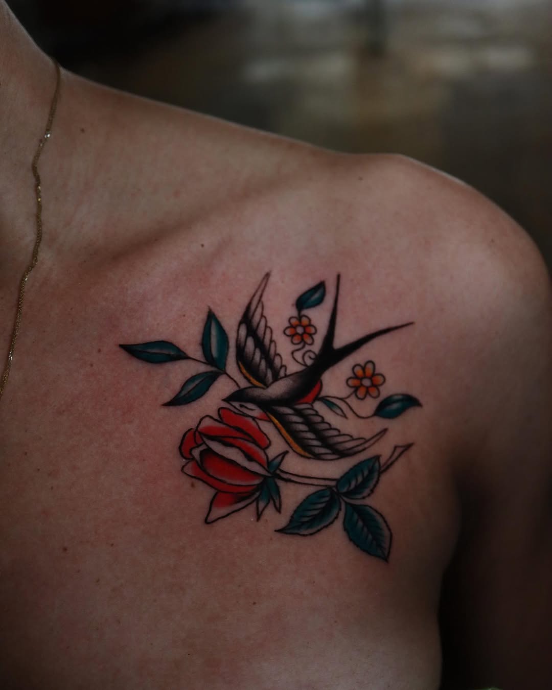 Vibrant rose and swallow tattoo on shoulder