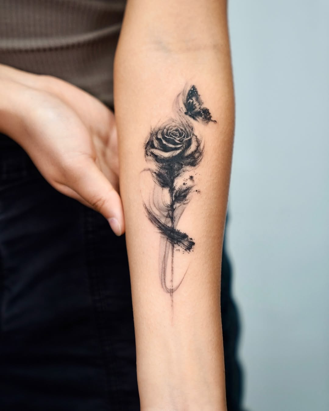 Elegant black rose tattoo with butterfly accent