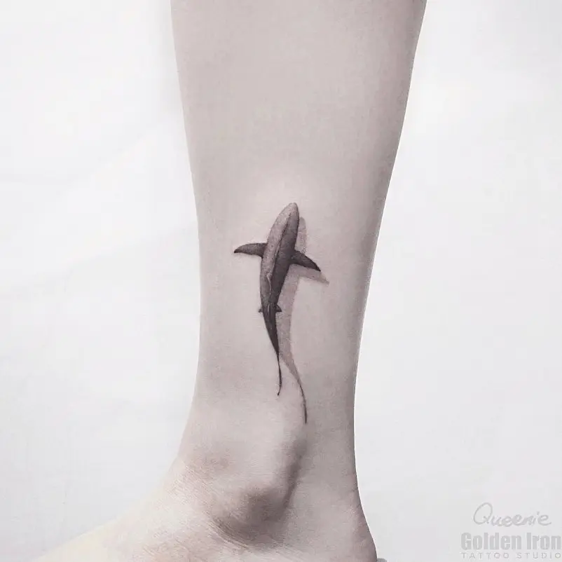 Minimalist shark tattoo on sleek leg