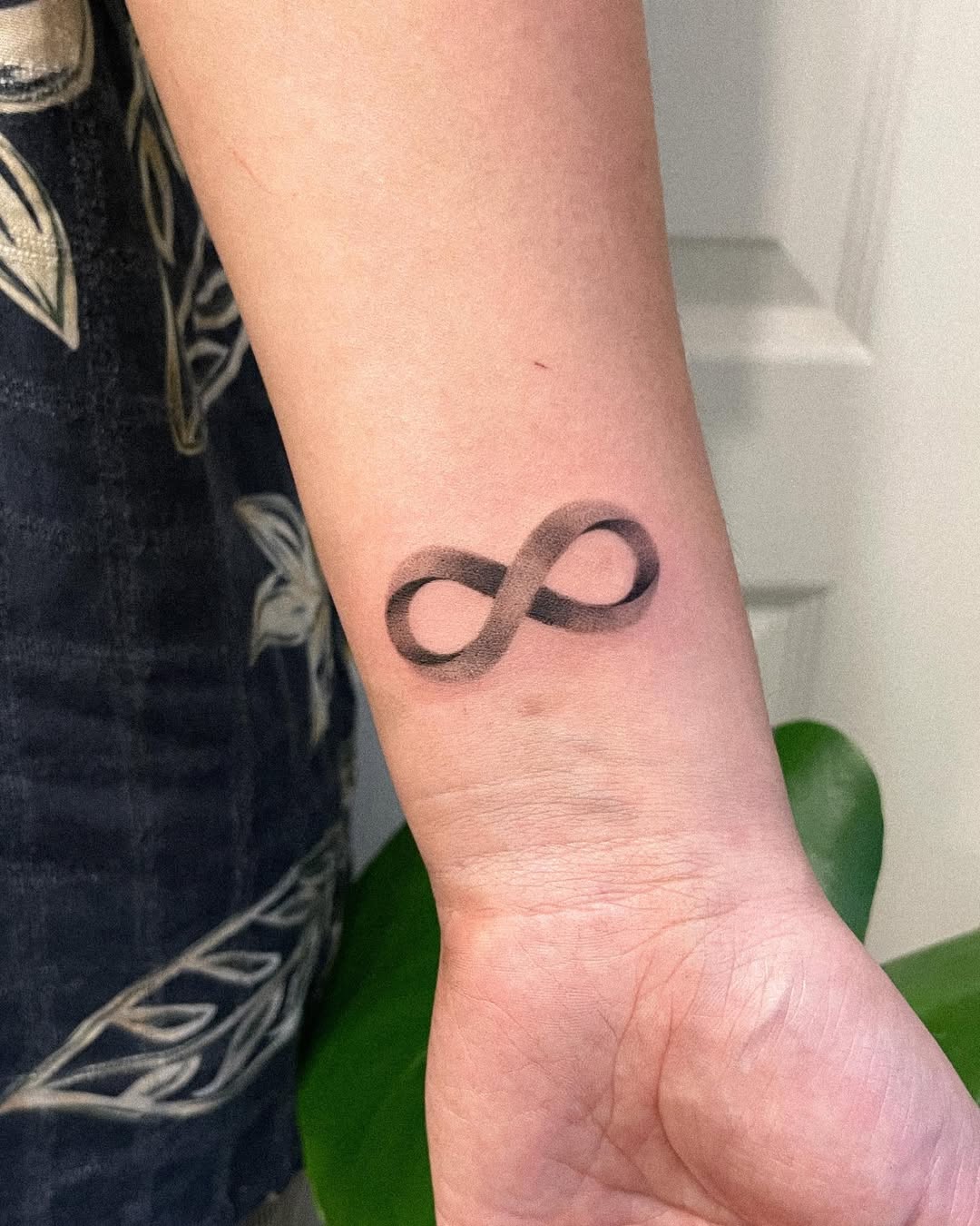 Minimalistic infinity tattoo on the forearm.