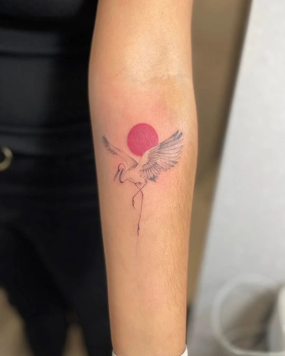 Elegant crane tattoo with a vibrant sun backdrop