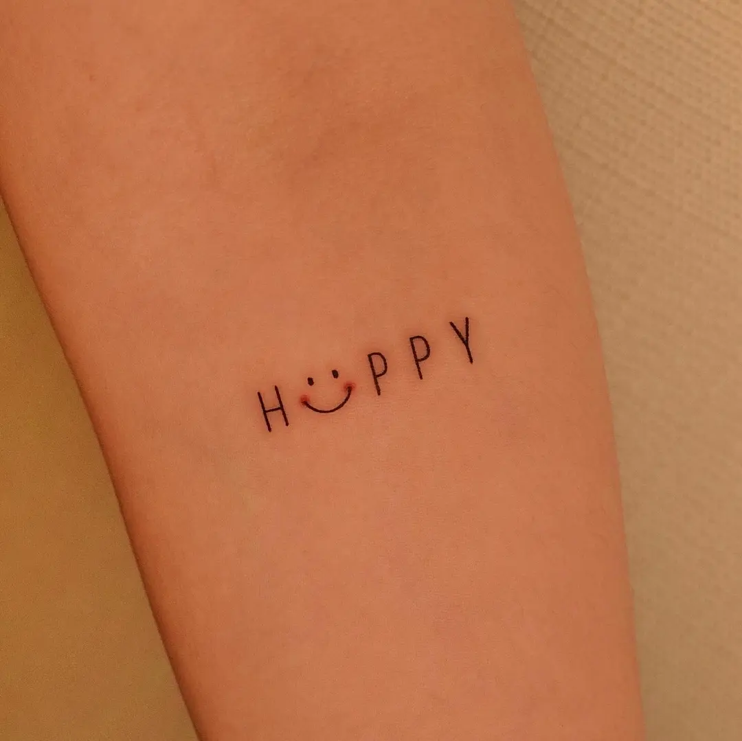 Minimalist 'HAPPY' tattoo with smiley design
