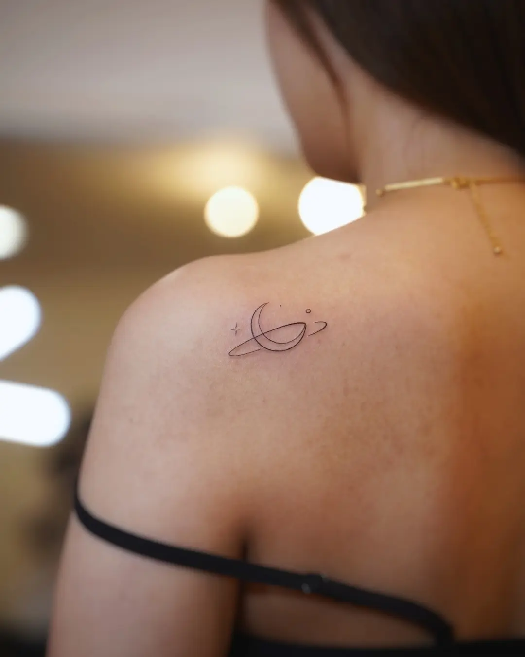 Delicate planet tattoo on shoulder