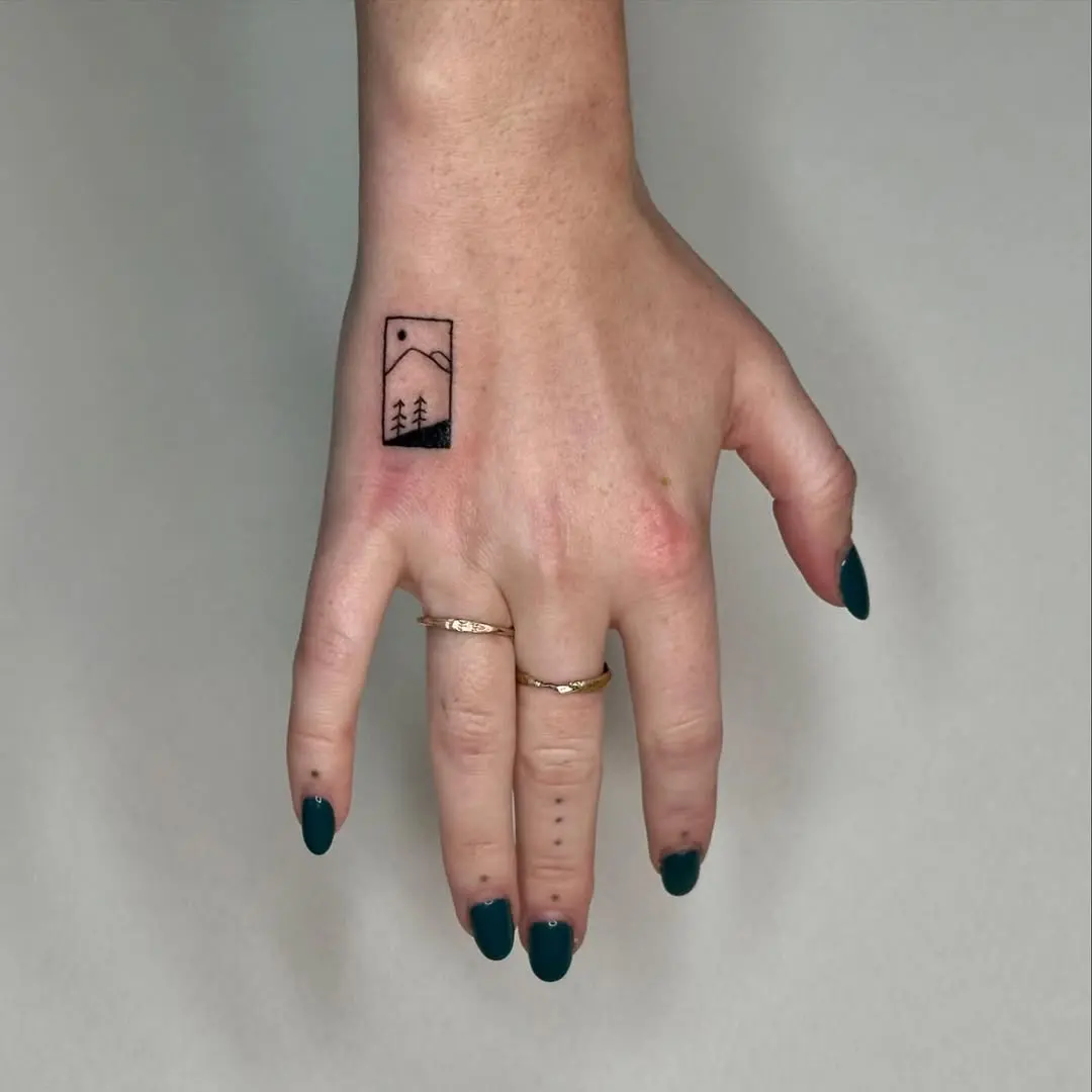 Minimalist mountain scene on wrist tattoo