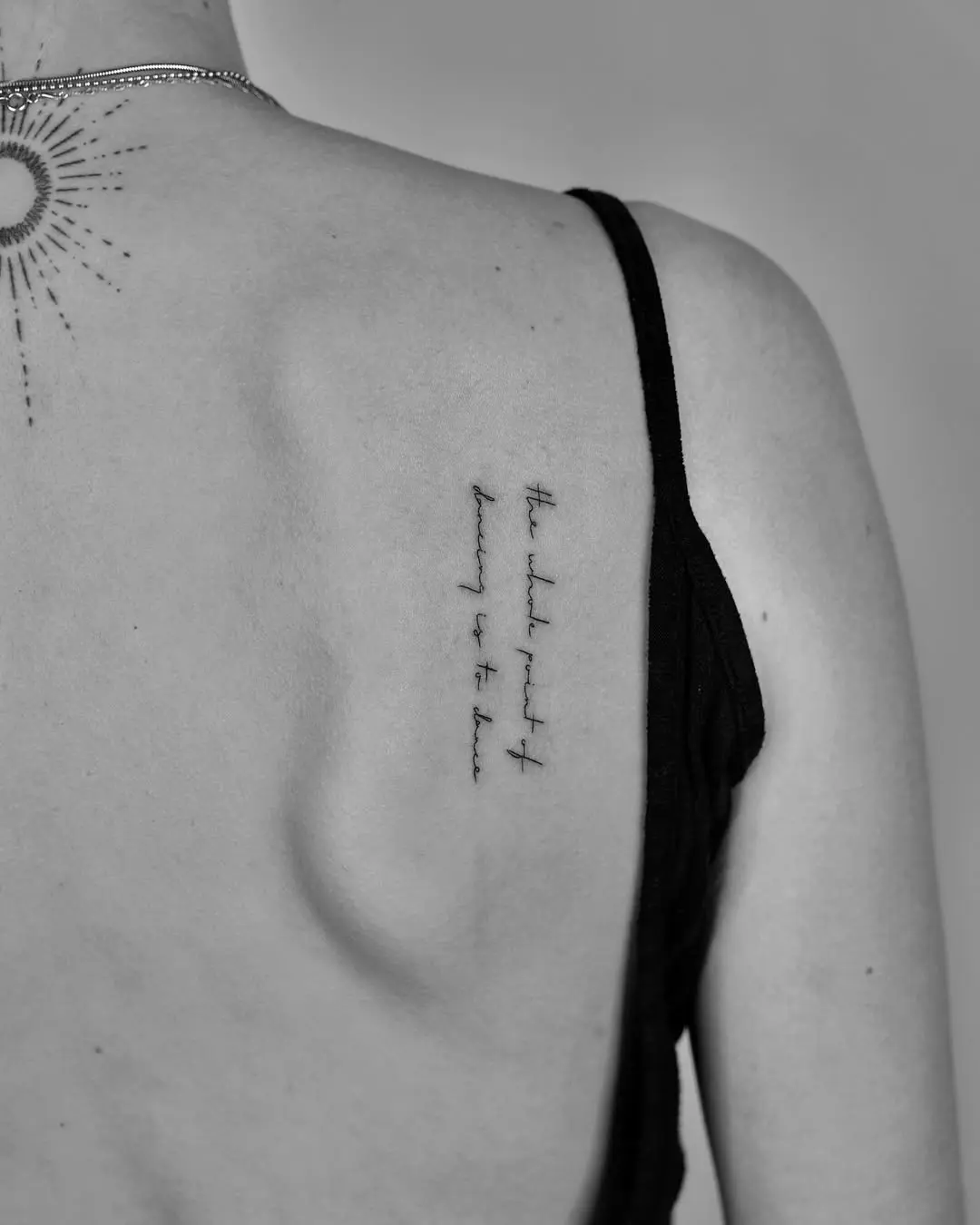 Delicate script tattoo on the upper back