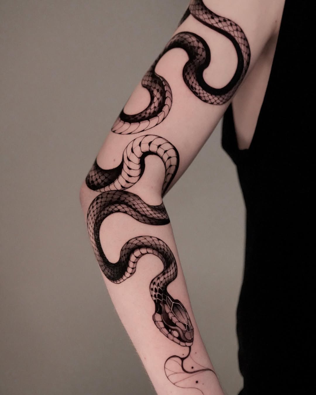 Elegant black snake tattoo on a woman's arm