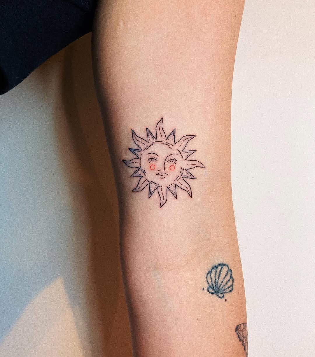 Whimsical sun face tattoo on forearm