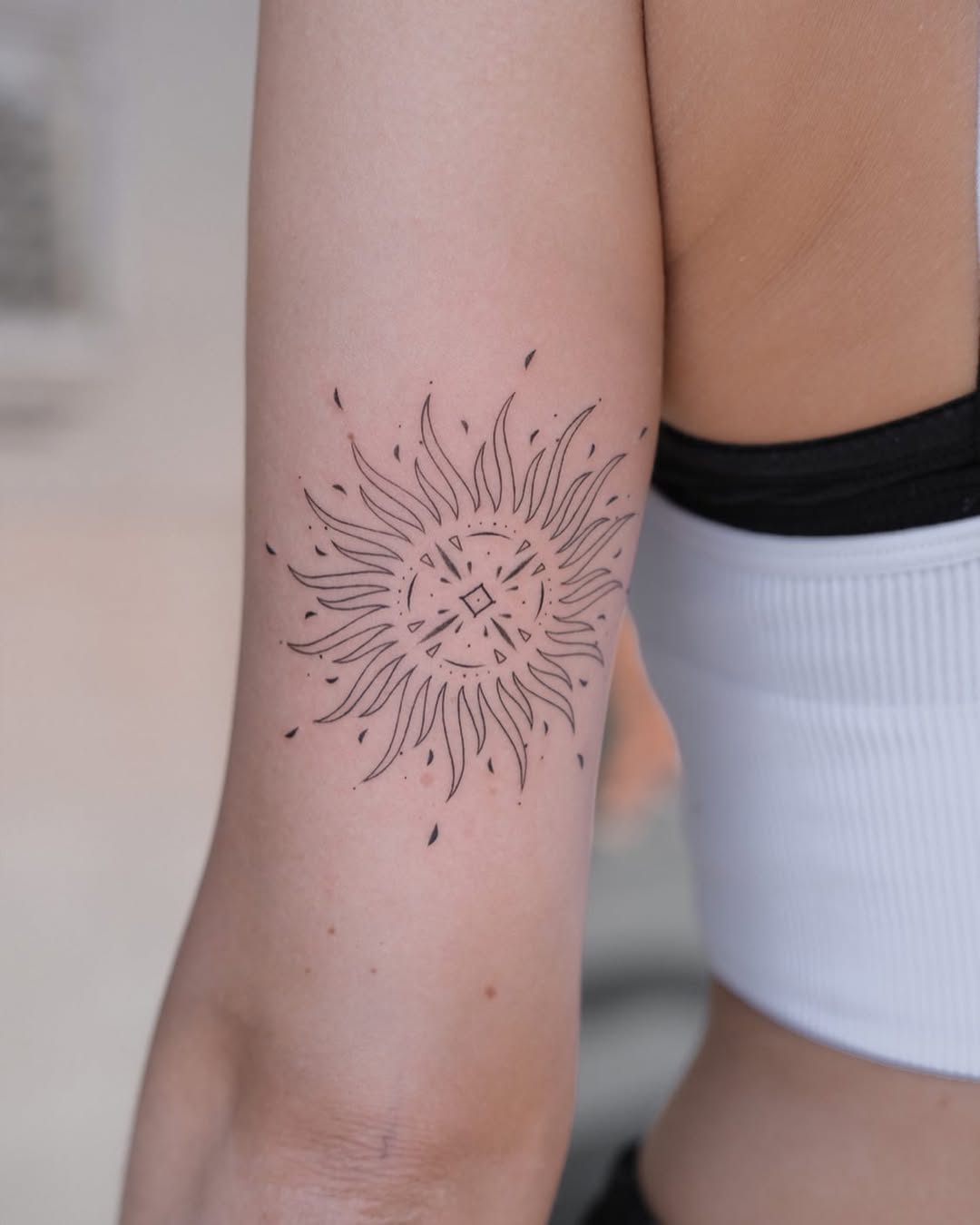 Minimalist sun tattoo on the arm