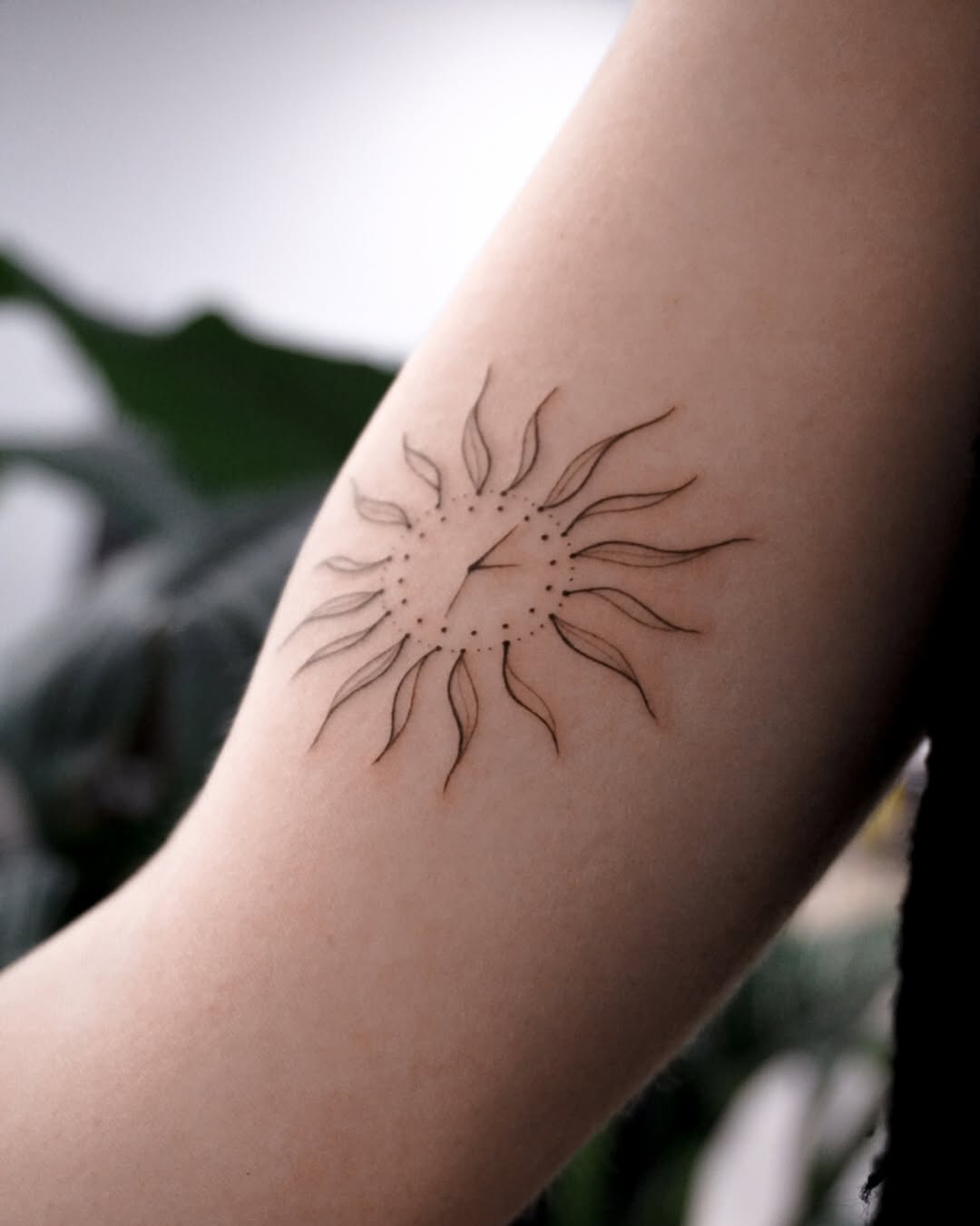 Elegant minimalist sun tattoo on the arm