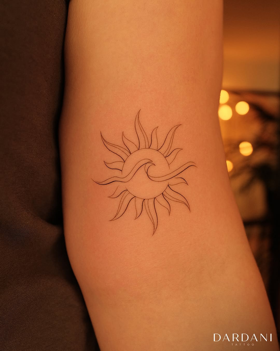 Elegant minimalist sun tattoo design on arm