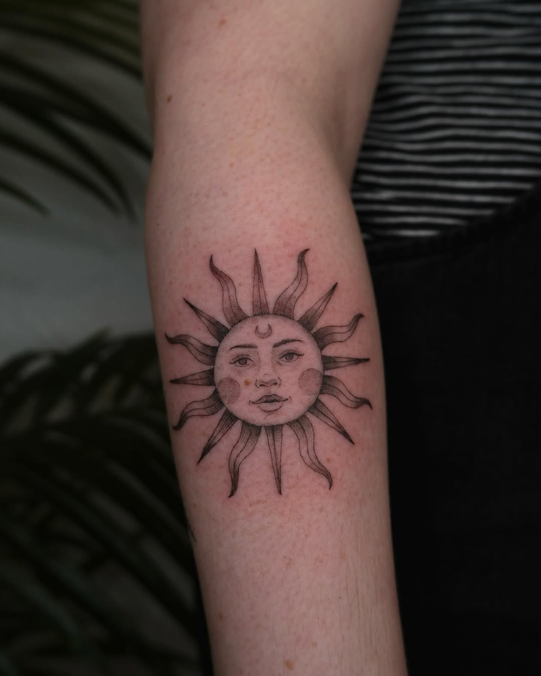 Intricate sun tattoo with moon and facial details