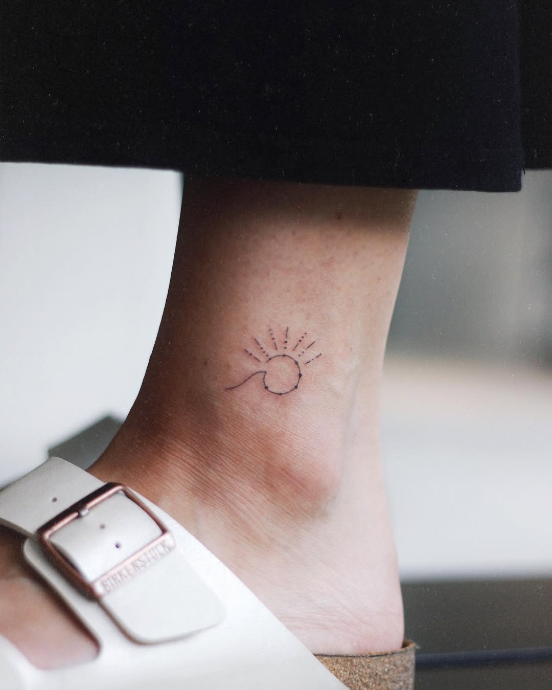 Minimalist sun tattoo on ankle