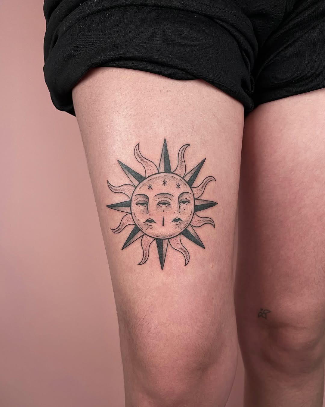 Radiant sun tattoo featuring dual faces and stars