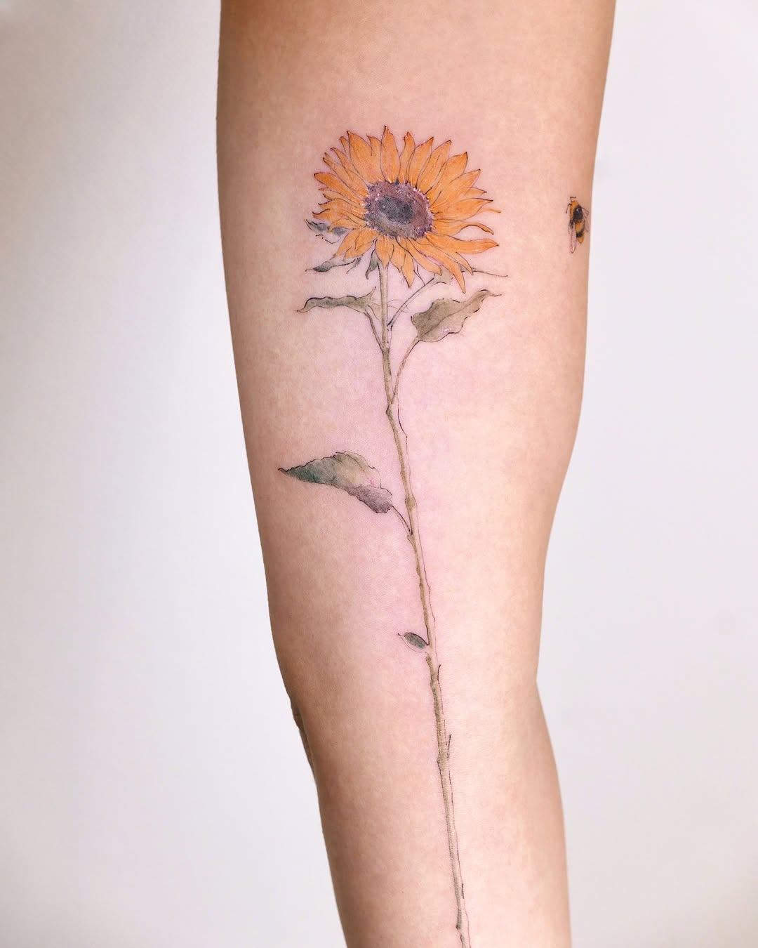 Vibrant sunflower tattoo with a charming bee