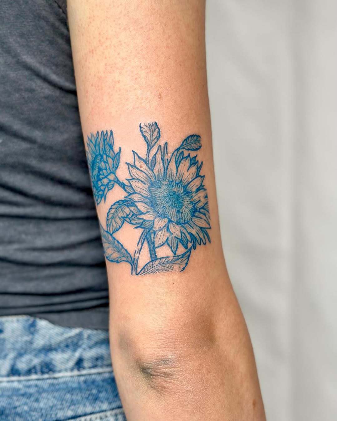 Blue sunflower tattoo on an elegant arm