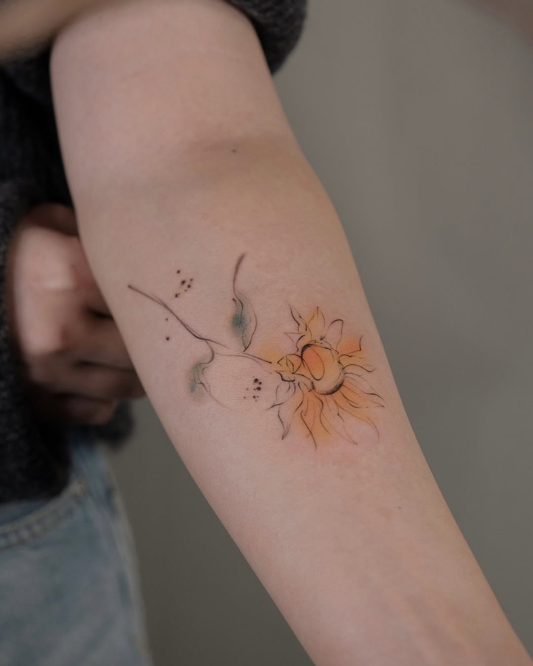 Delicate and colorful sunflower tattoo on arm