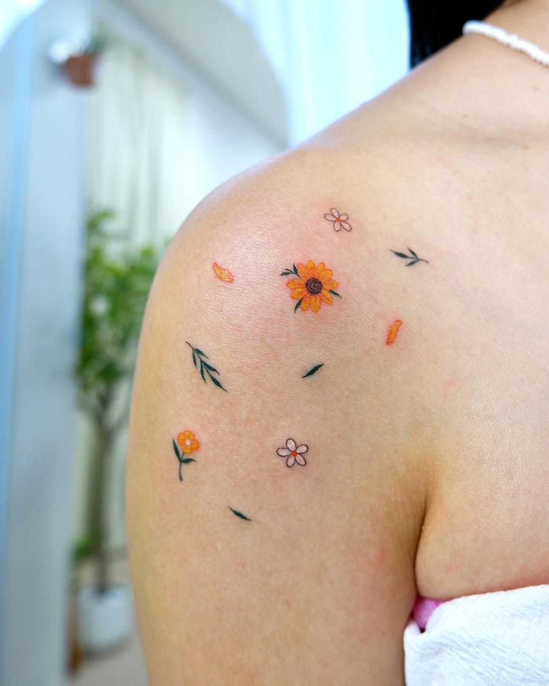 Delicate sunflower tattoo with floral accents