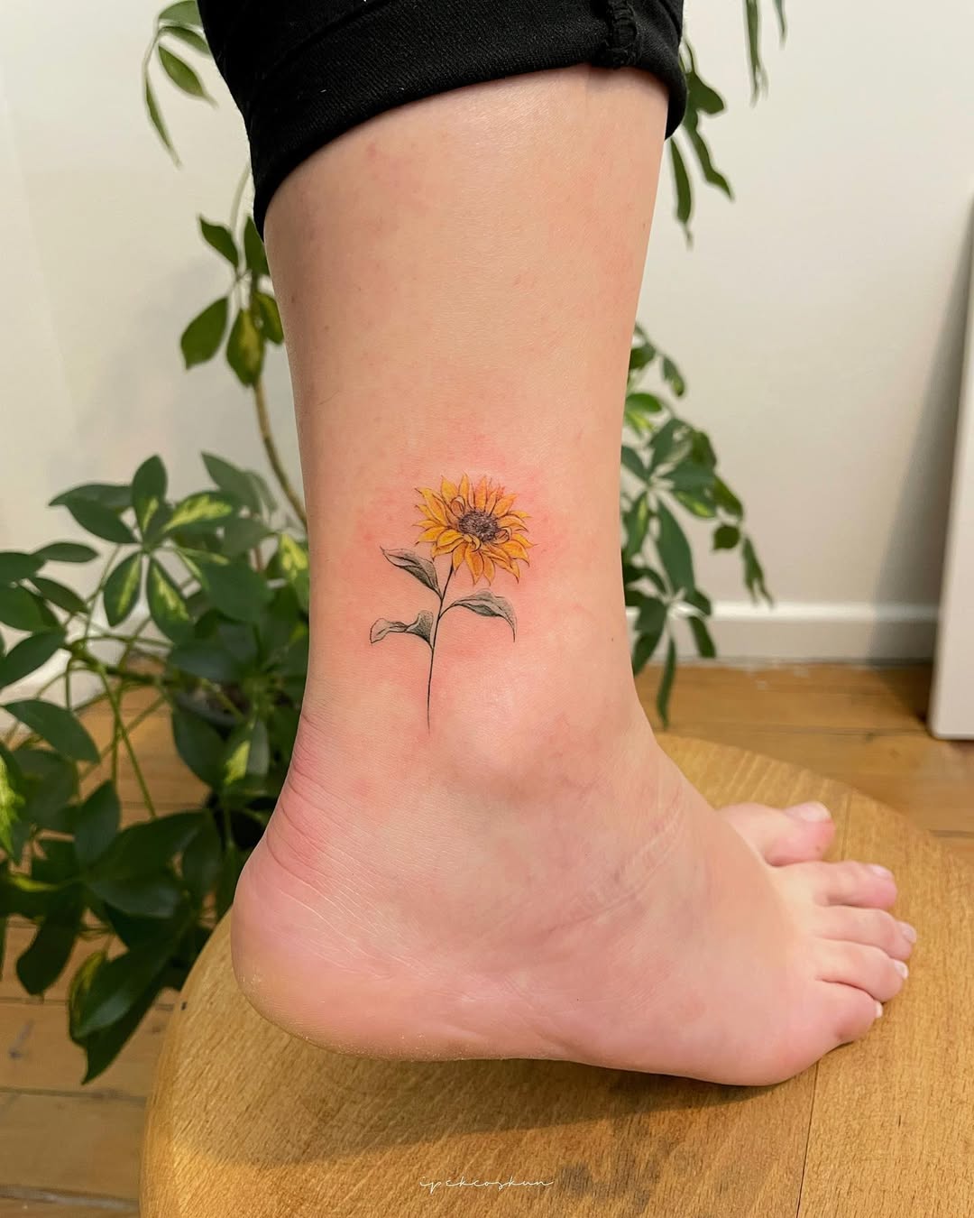 Delicate sunflower tattoo gracing the ankle