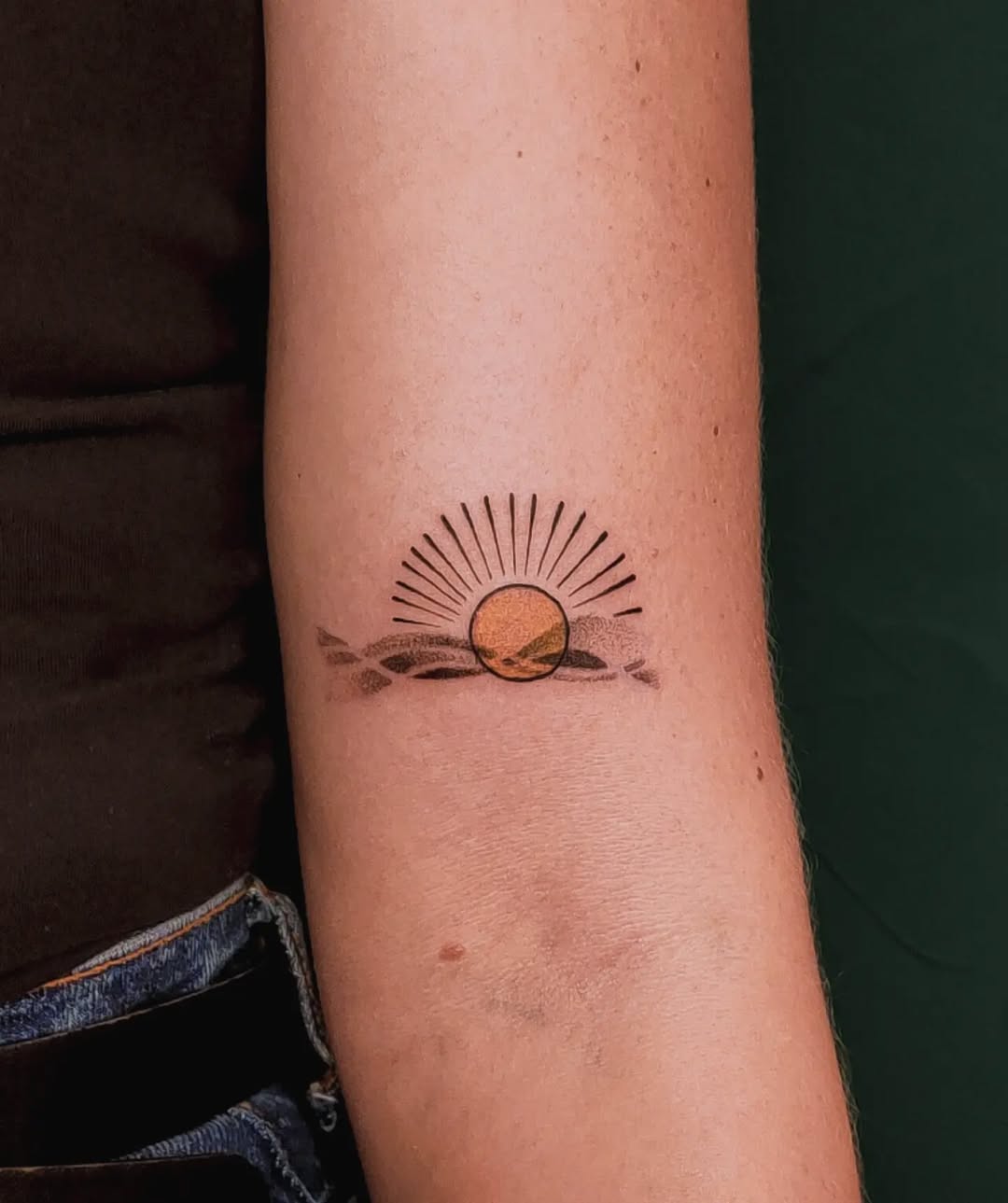 A serene sunrise tattoo on the forearm