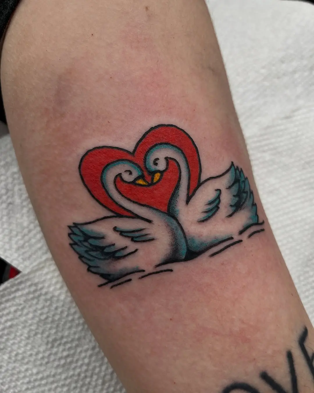 Elegant swans forming a heart shape tattoo