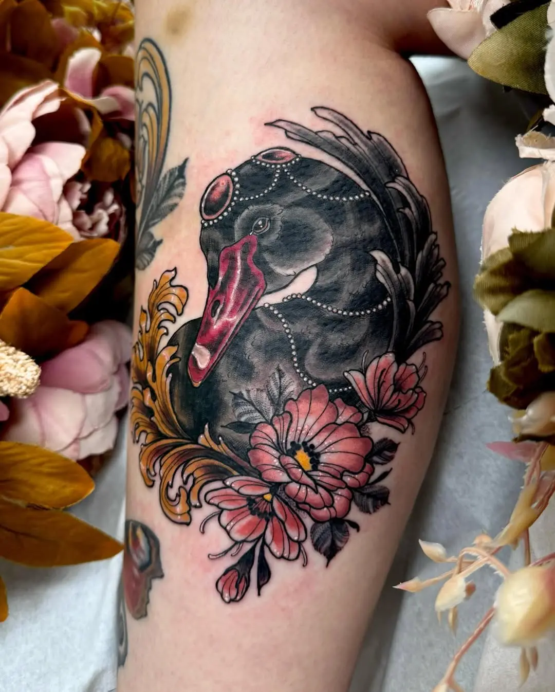 Elegant swan tattoo surrounded by floral elements