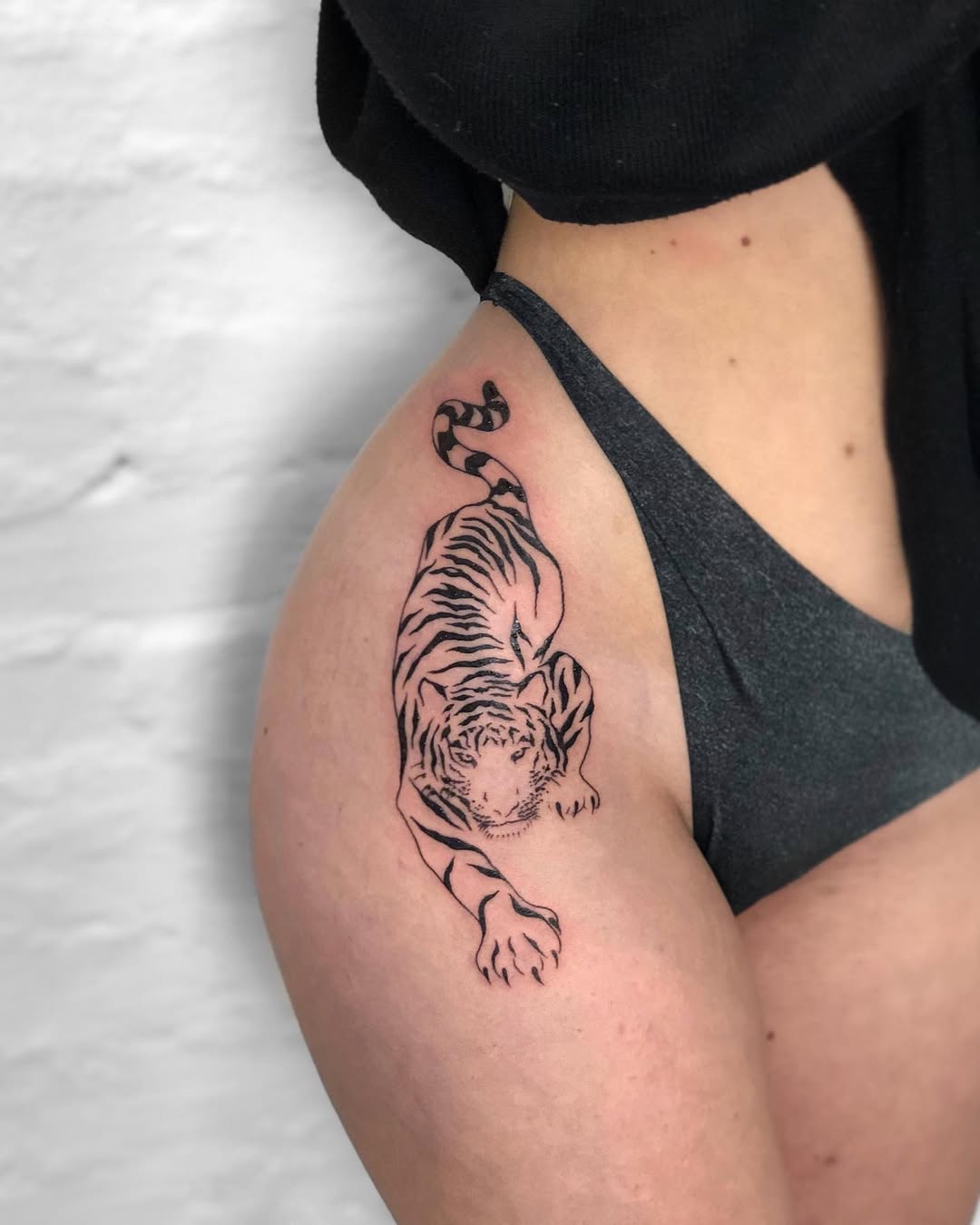 Fierce tiger tattoo climbing on the hip