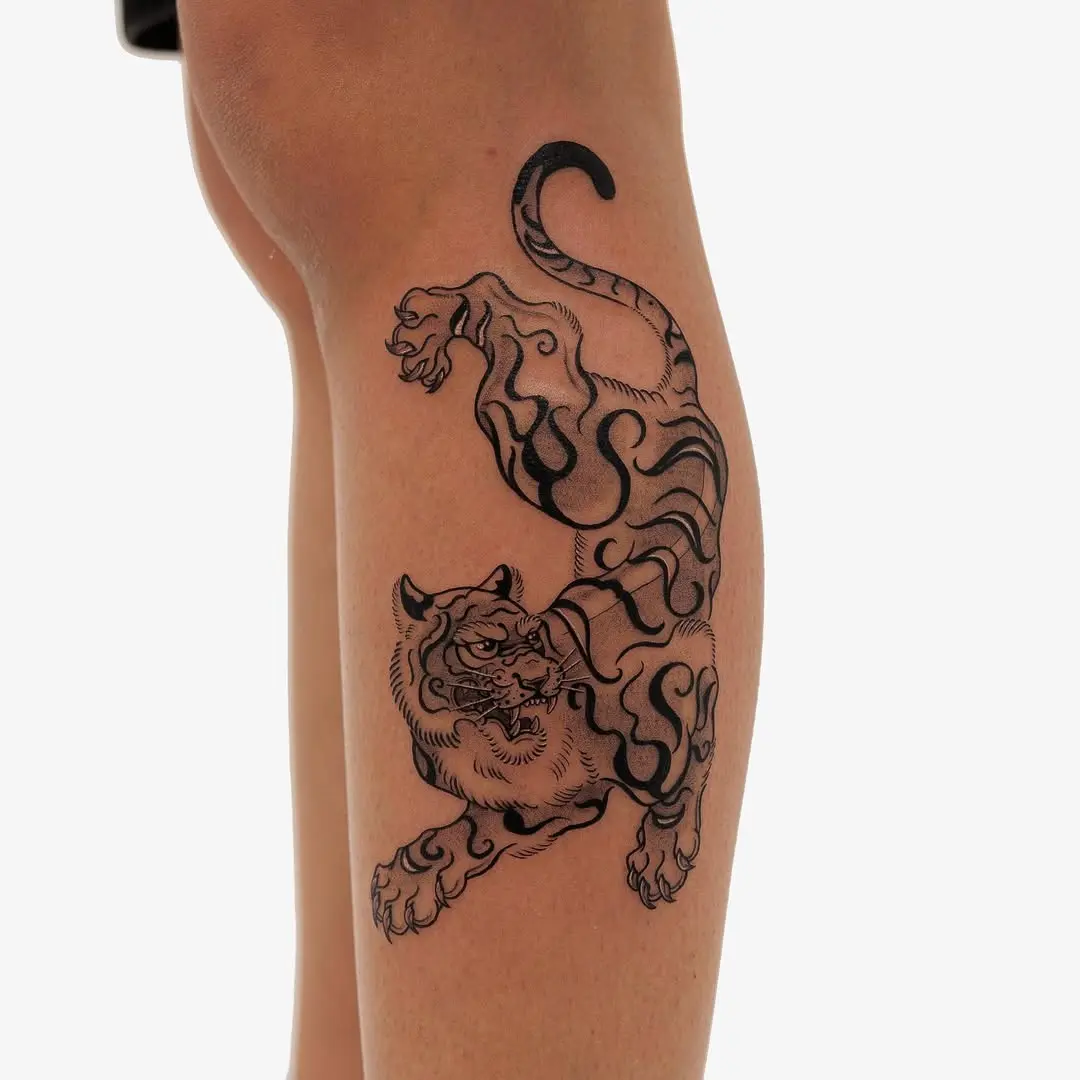 Dynamic black ink tiger tattoo on leg