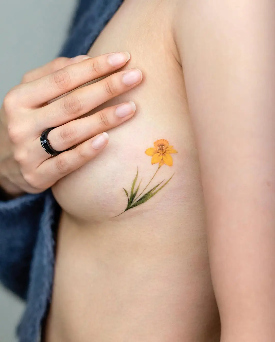Vibrant yellow floral underboob tattoo design