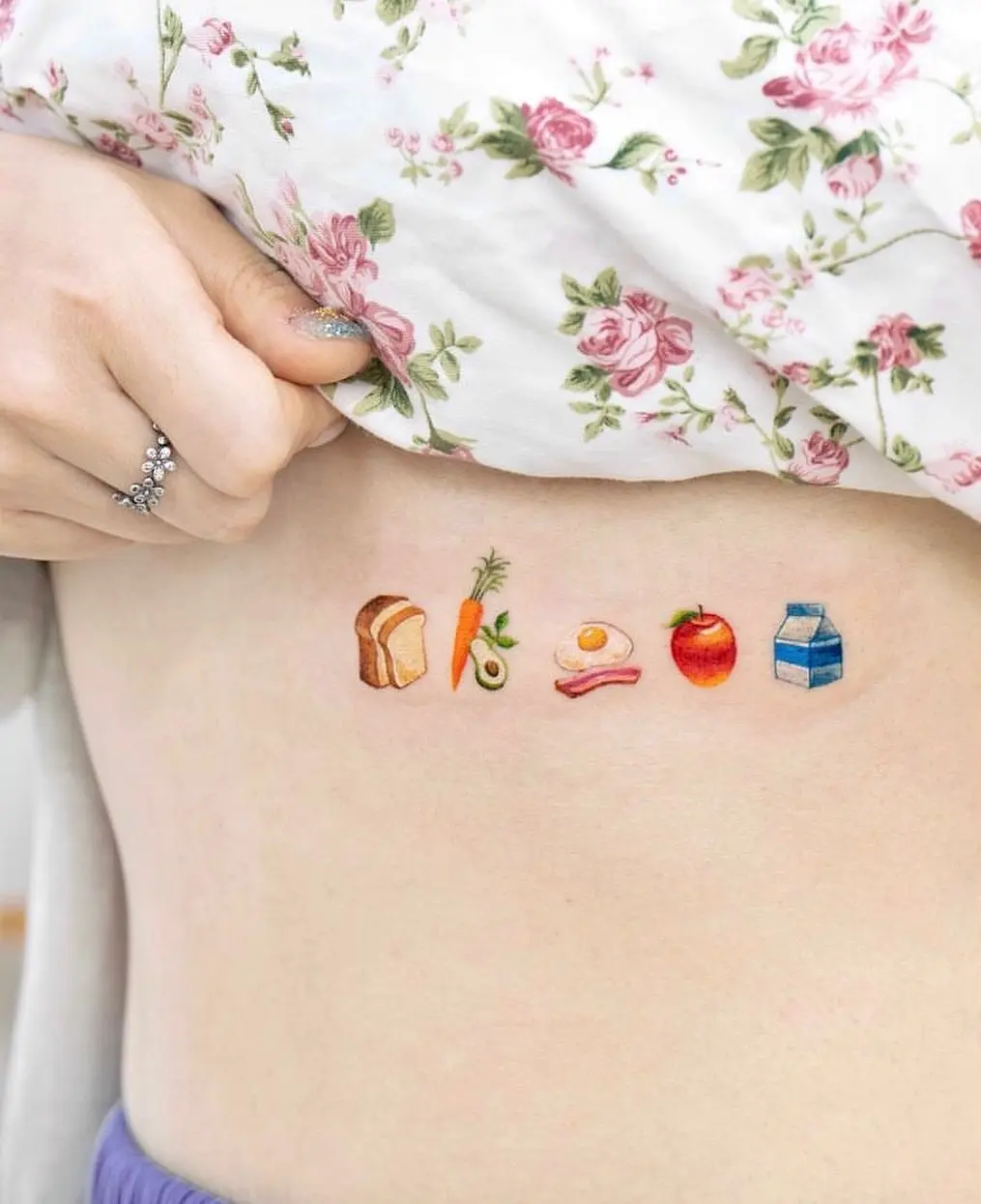 Colorful food-themed underboob tattoo design