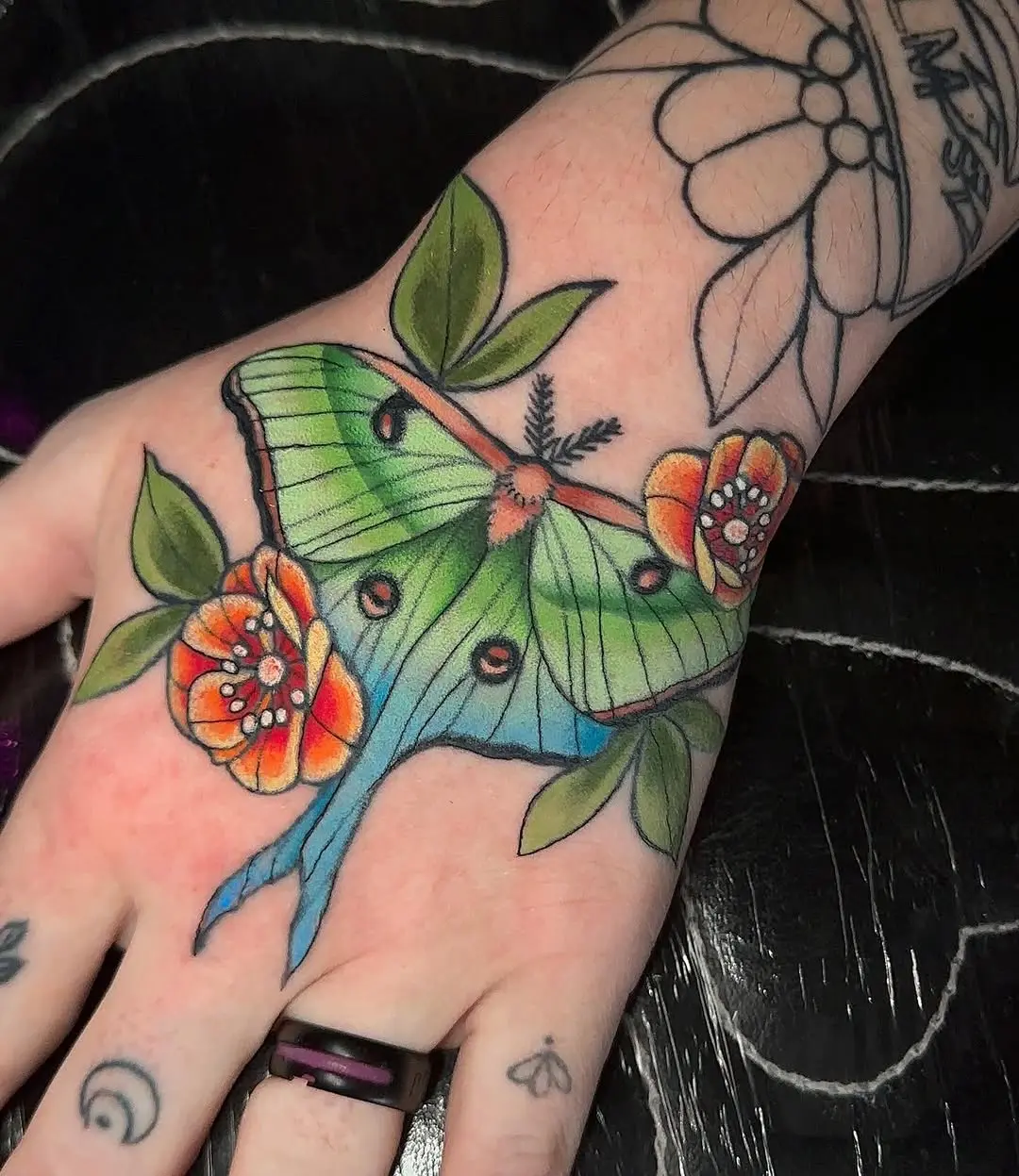 Vibrant moth tattoo with floral details