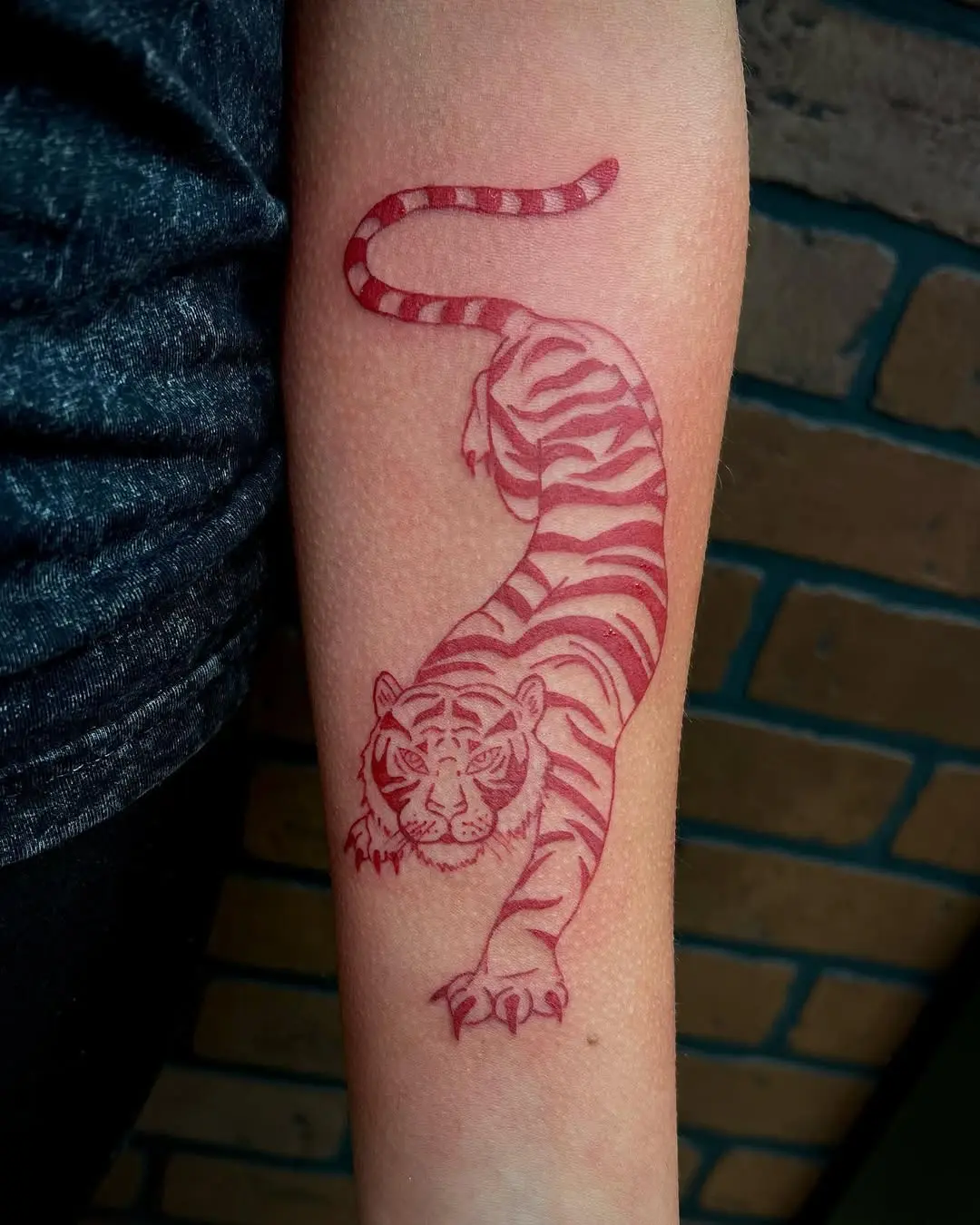Striking red-striped tiger tattoo on forearm