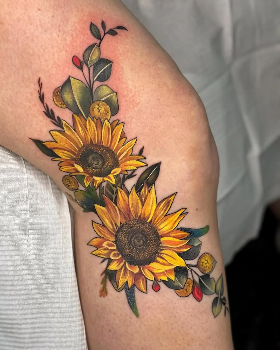 Beautiful sunflower tattoo with floral accents.