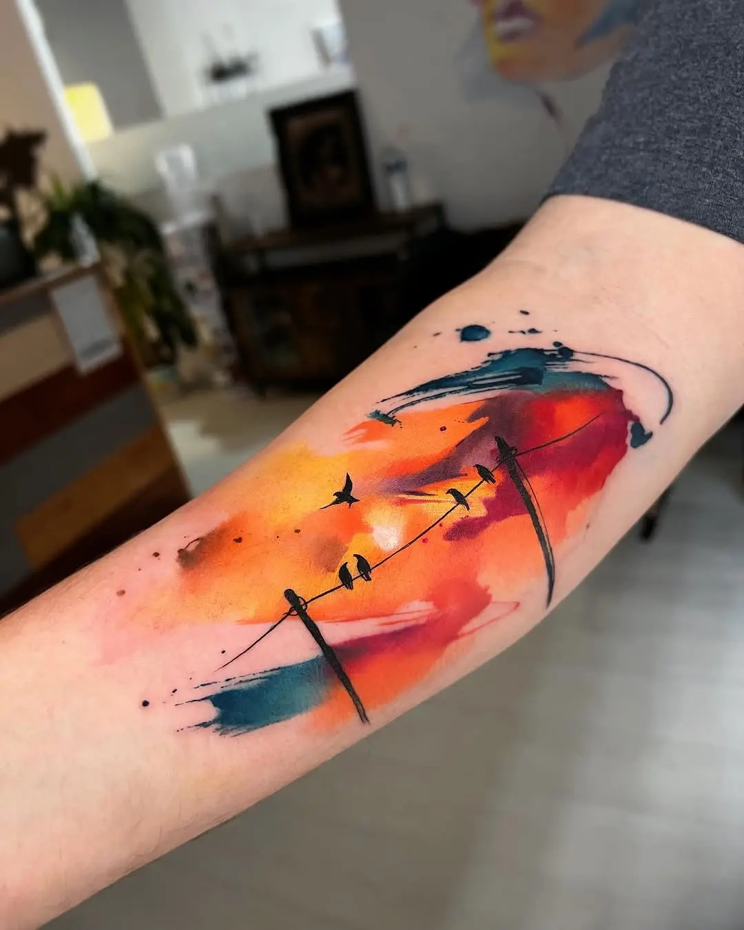 Dynamic sunset-inspired watercolor bird tattoo