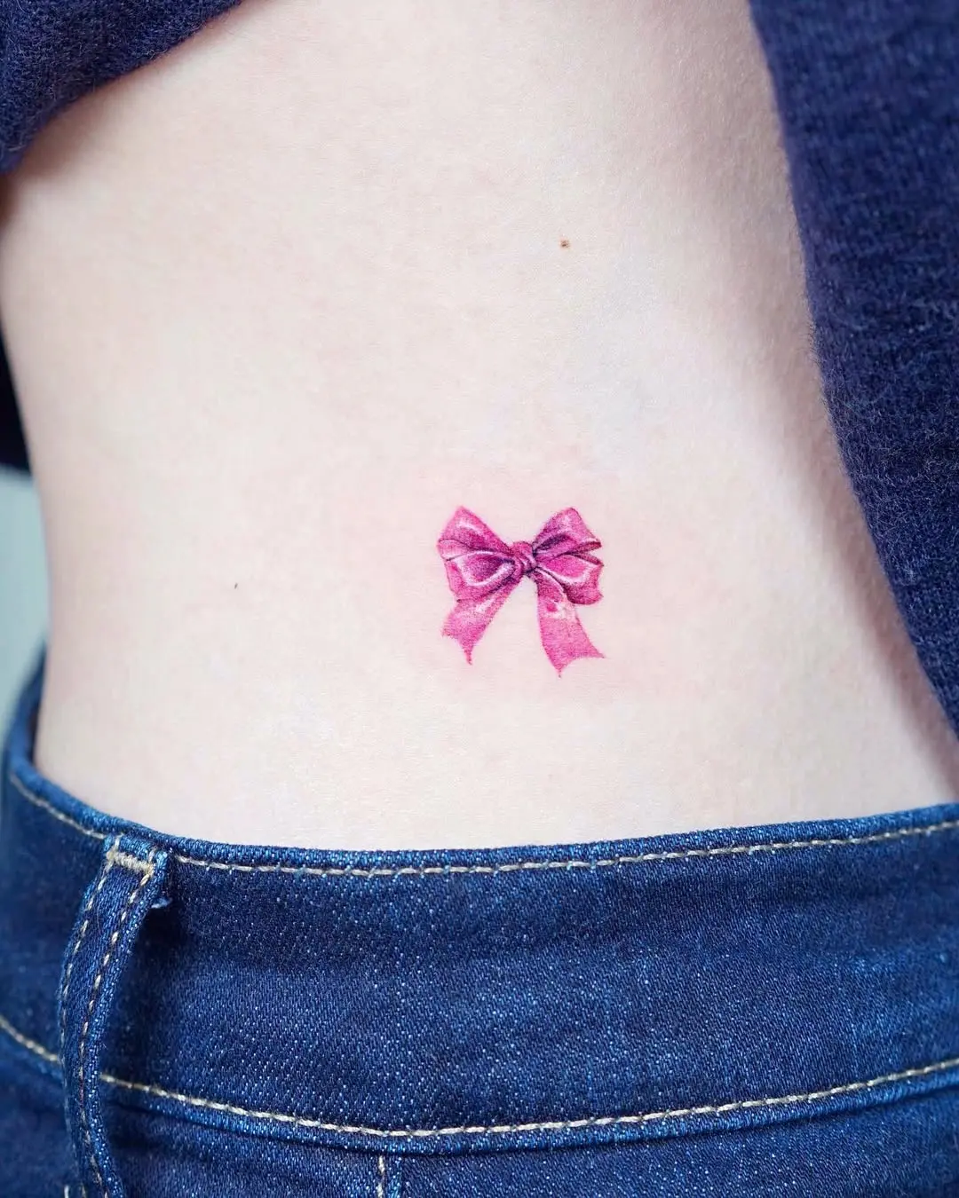 Delicate pink bow tattoo on waist