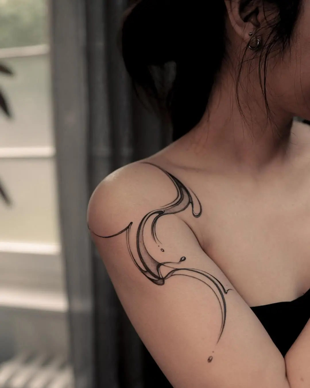 Fluid water-inspired tattoo design on shoulder