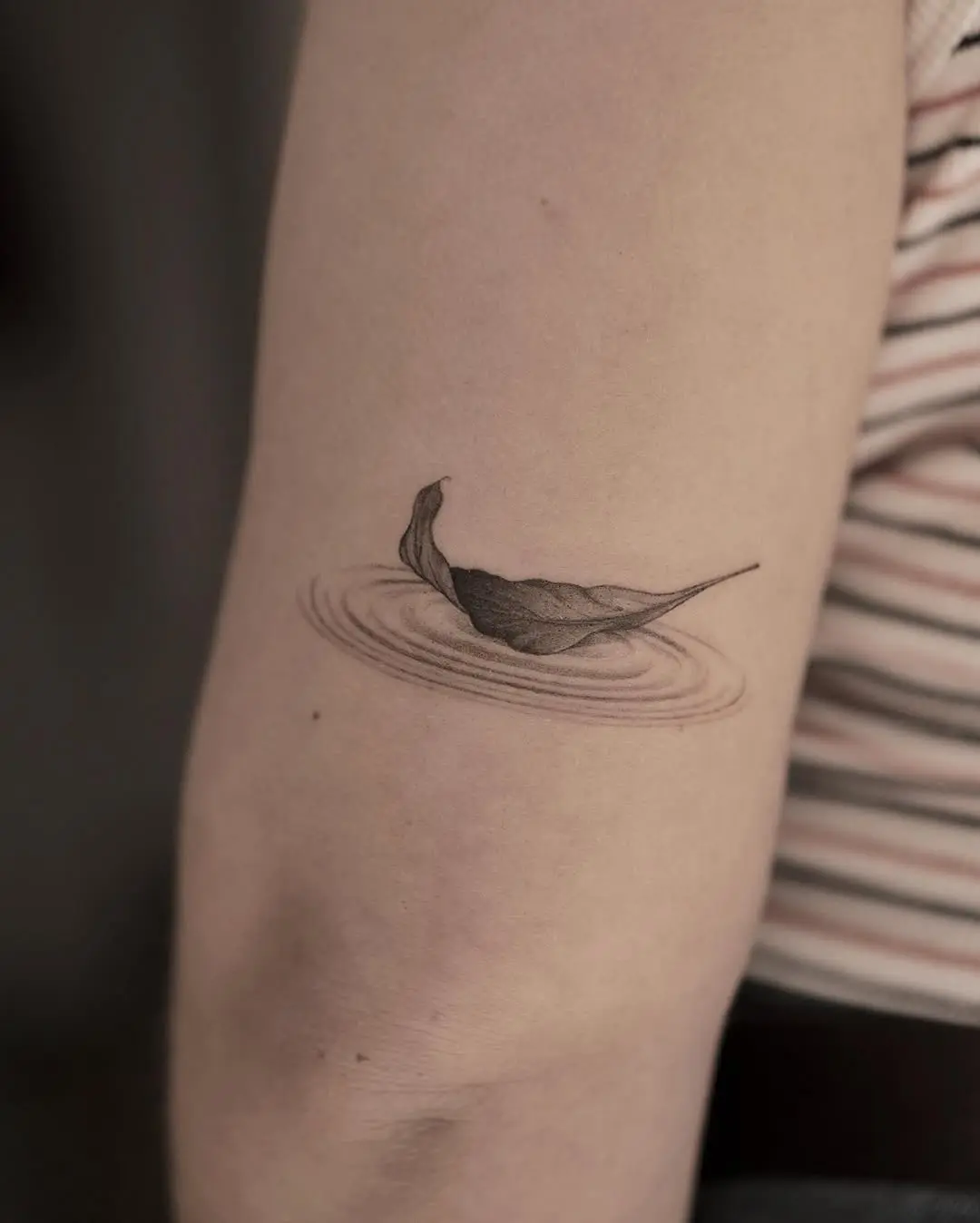 Minimalist tattoo of a leaf on water