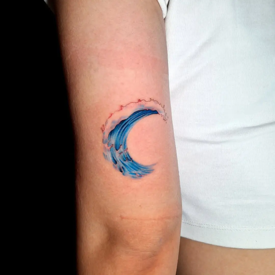 Dynamic blue wave tattoo on the arm