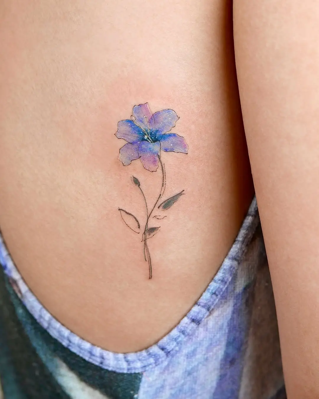 Vibrant watercolor flower tattoo on the arm