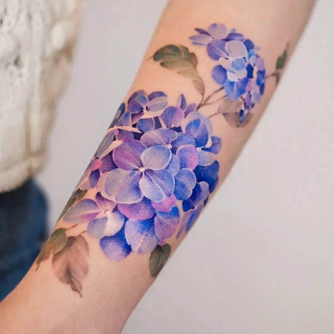Vibrant lavender hydrangea watercolor tattoo on arm