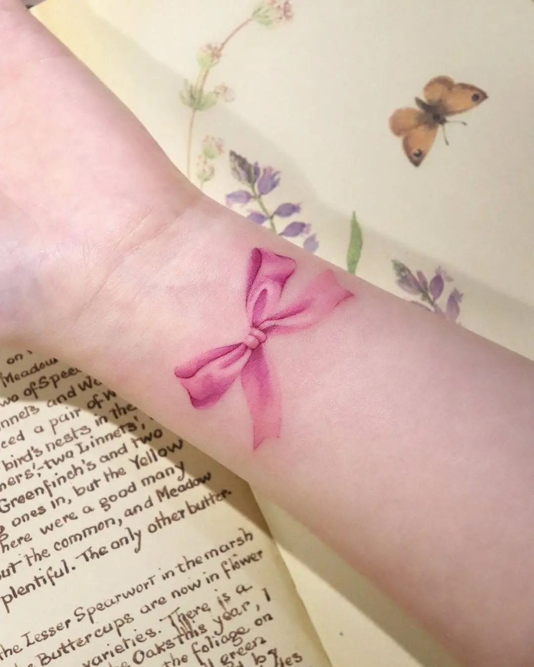 Delicate pink ribbon tattoo on pale skin