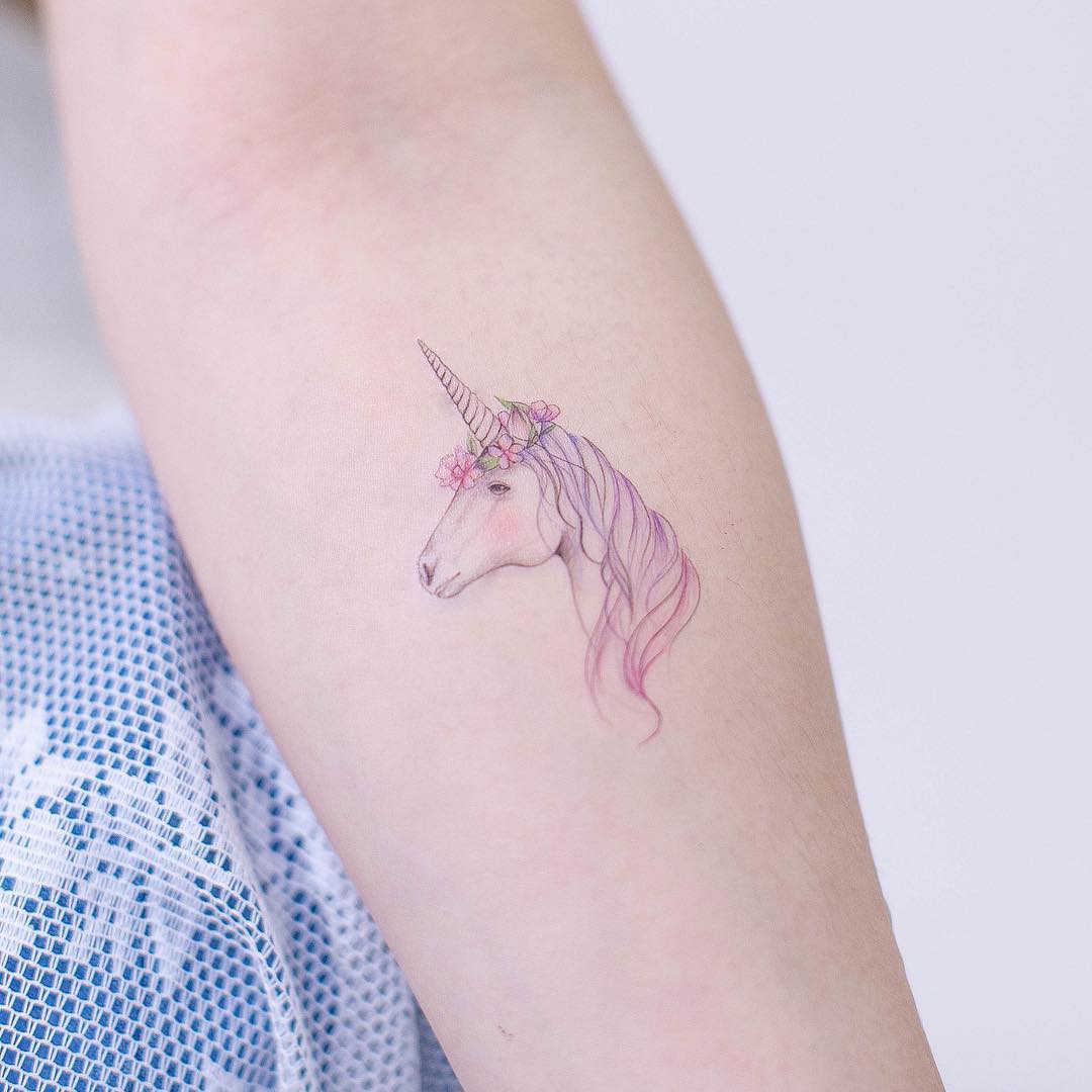 Delicate unicorn tattoo with floral accents