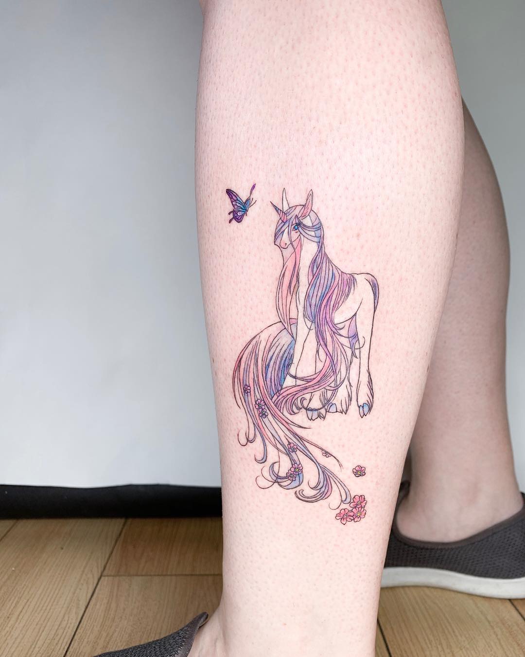 Whimsical unicorn tattoo with floral accents