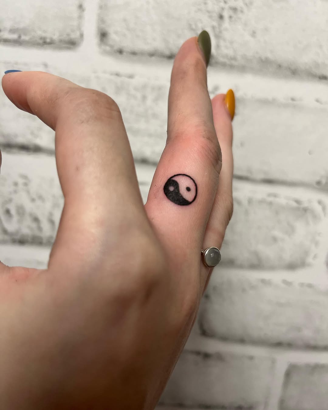 Minimalist yin yang tattoo on a finger