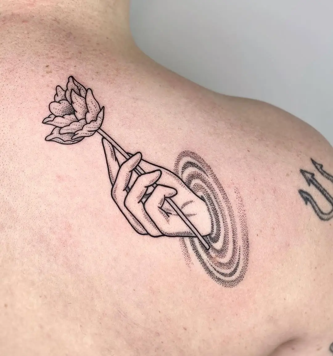 A graceful hand holding a blooming lotus tattoo