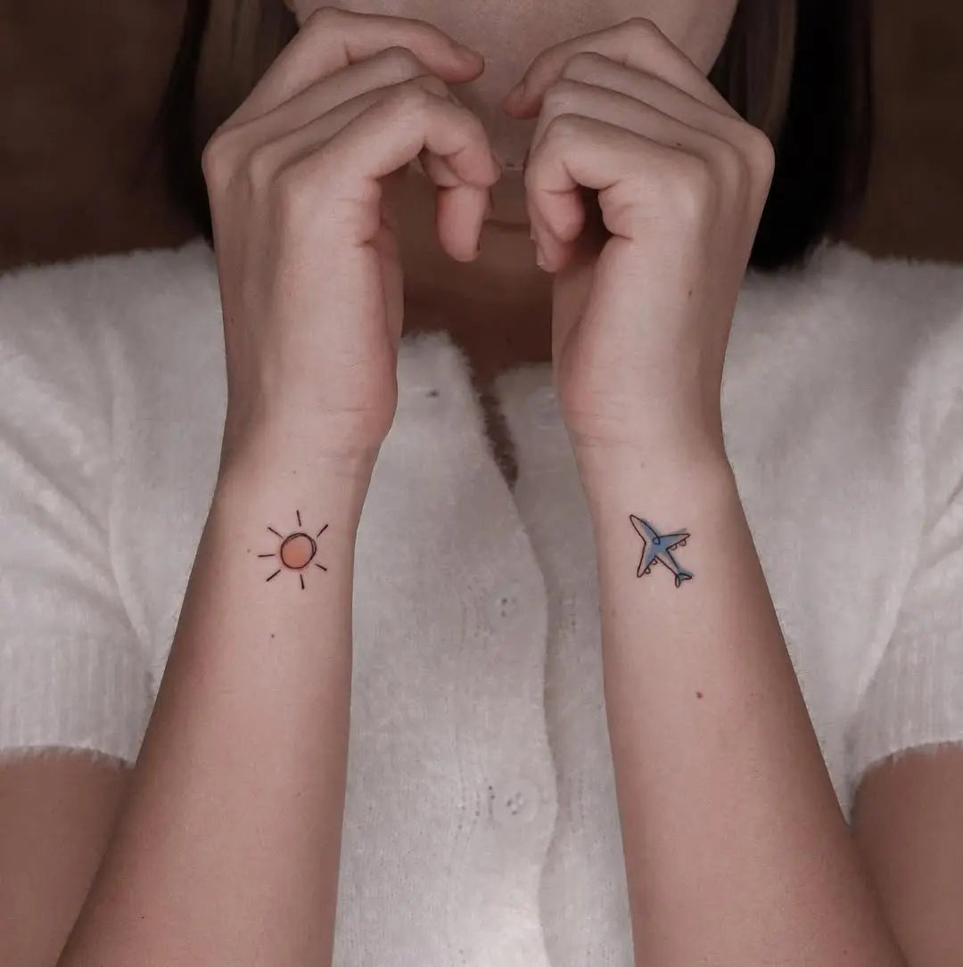 Minimalist airplane and sun tattoo on forearm
