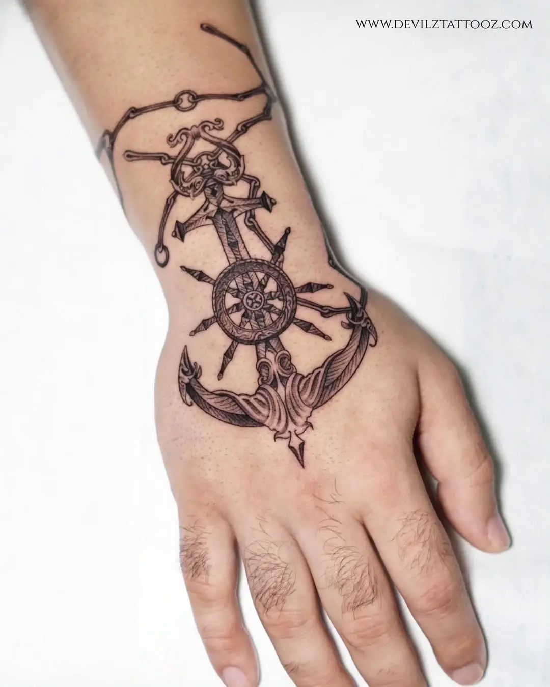 Intricate anchor tattoo with skull and ship wheel