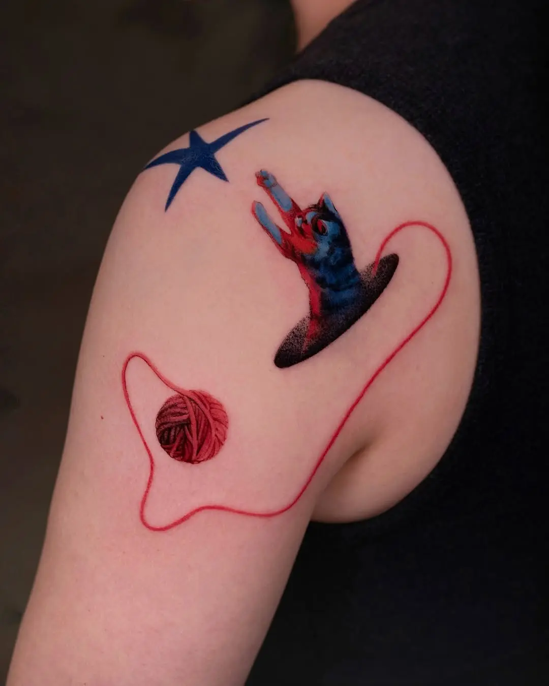 Playful cat tattoo with yarn and star
